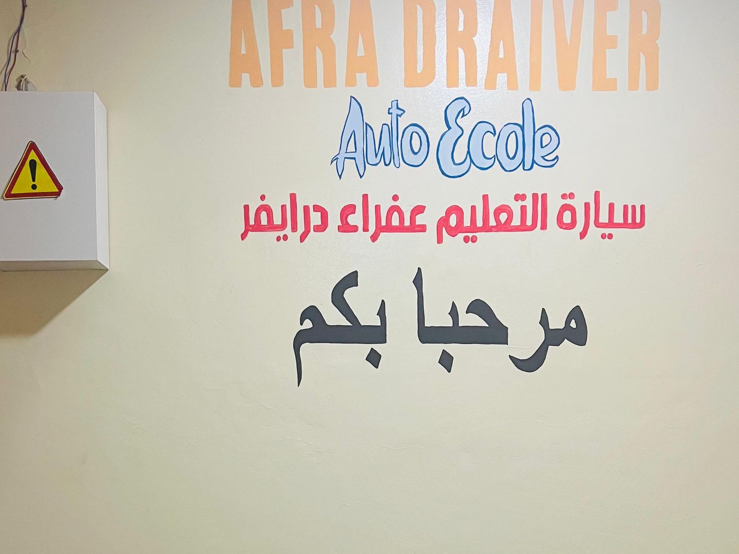 Mur d'accueil de l'auto-école AFRA DRIVER portant la mention « bienvenue » en arabe