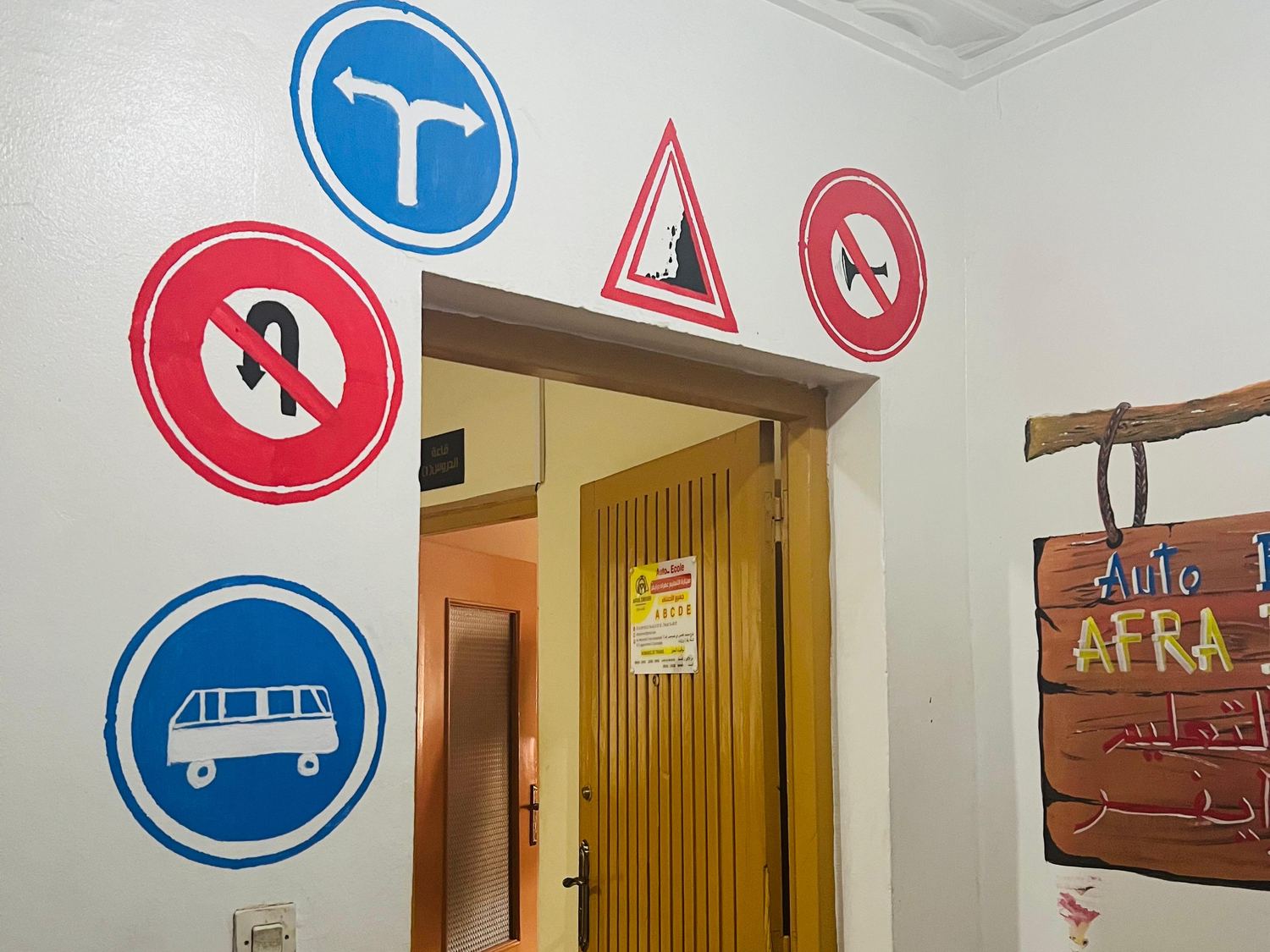 Couloir de l'auto-école décoré de panneaux de signalisation, enseigne AFRA DRIVER